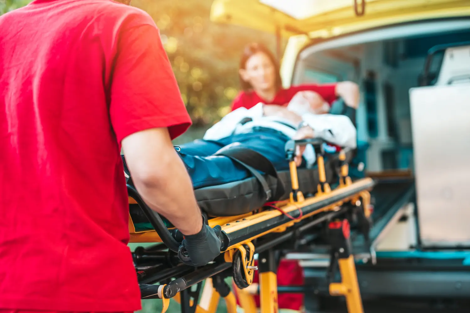 Rettungsdienst am Arbeitsplatz. Sanitäter zieht Trage mit älterem Mann mit schwerem Herzinfarkt zum Krankenwagen
